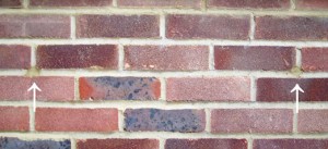 Brick wall with 2 small drill holes which have been filled
